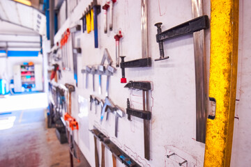Tools hanging on wall in industrial workshop from a side angle