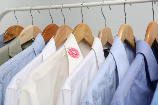 Men's shirts and one with lipstick kiss mark on rack, closeup