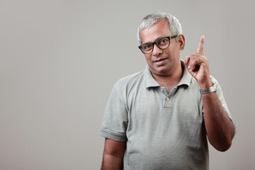 A mature man of Indian ethnicity makes a point with his index finger