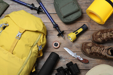 Flat lay composition with backpack and other different camping equipment for tourism on wooden background