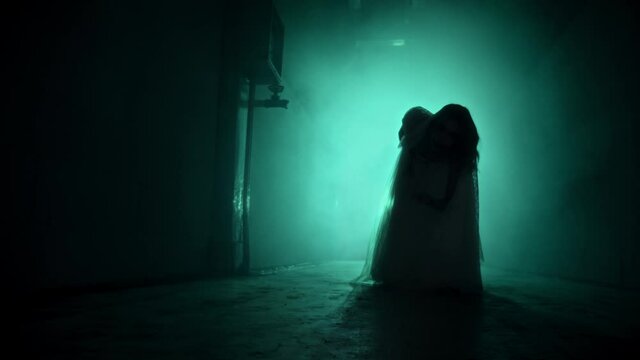 Dead walking zombie woman in dark corridor and mist close-up. Creepy bride wearing wedding dress with veil. Deceased fiancee returned to life. Horrible klip on halloween. Haunted house. 