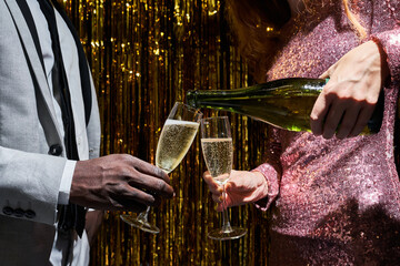 Crop multiethnic couple serving champagne during party