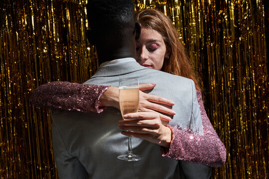 Loving diverse couple with champagne embracing during party