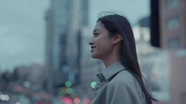 Asian woman walking on city street with smartphone in hands