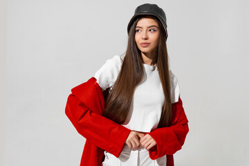 Trendy winter accsesorises. Pretty girl in black hat and red coat  raised hands and holding cap in studio on white background.