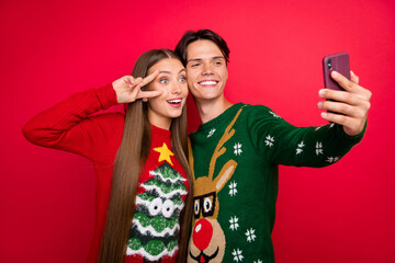 Photo of glad couple girl show v-sign guy take phone selfie wear ugly pullover isolated red color...