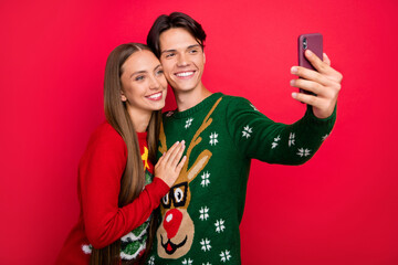 Photo of glad cute couple guy hold phone shoot selfie wear ugly ornament sweater isolated red color...