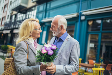 Romantic middle-aged man giving his wife flowers