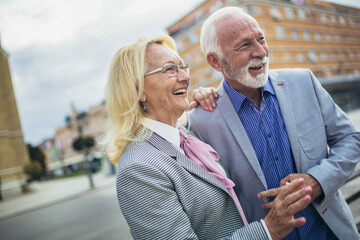 Mature married couple are walking through a city together.
