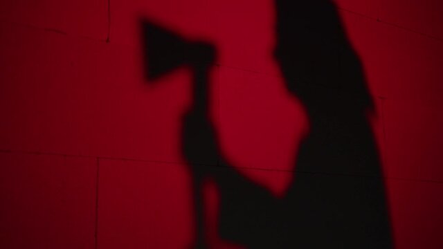 Creepy death silhouette running for victim with axe on red background. Mystical scary murderer, maniac catching up woman. Halloween costume of killer. Horror scene movie of psycho serial. 