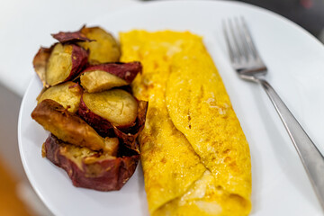 Japanese sweet potato and hot cheese egg omelette on white plate cooked folded traditional for morning breakfast closeup and fork