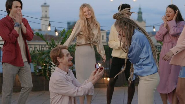 Redhead man proposing girlfriend with dreads on rooftop