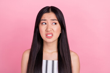 Photo of millennial unsure brunette lady look empty space wear white overall isolated on pink color...