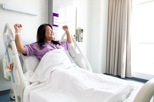 Asian fat woman patient feeling happy lying on bed in the new medical center. Recovery Room with beds and comfortable medical