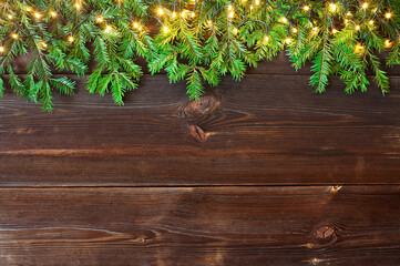 Fir branches and Christmas lights on wooden rustic planks. Christmas background. High angle view.