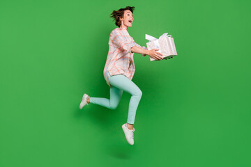 Full body profile side photo of amazed bob brunette haired woman jump up hold box gift look empty space run isolated on green color background