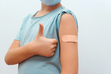 Boy showing arm with bandage. Virus protection. COVID-2019. Coronavirus vaccination campaign.