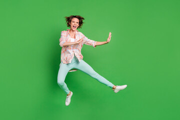Full body photo of angry aggressive young woman jump up fight empty space isolated on green color background