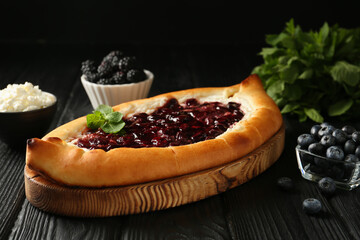 Delicious sweet cottage cheese pastry with cherry jam on black wooden table