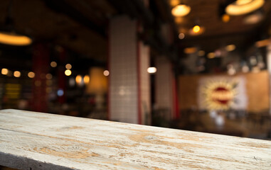 image of wooden table in front of abstract blurred background of restaurant lights