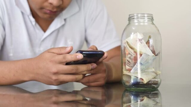 man reading online shopping contract on his cell phone, man doing online shopping, glass table with banknotes. cash. finance. Colombian economy. Colombian banknotes. savings and finance concept