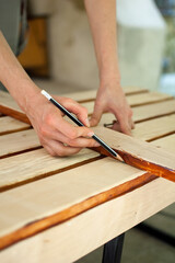 Female hands are making some marks on wooden plank for future holes using pencil for assembling bench, gender equality, feminism, do it yourself concepts.