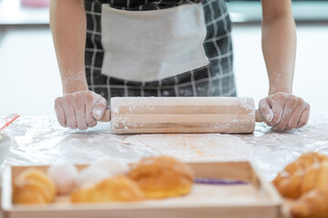 close up woman housewife with apron rolling out dough on kitchen table