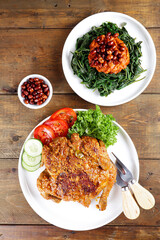 Ayam bakar Taliwang  is a traditional roast chicken from Lombok Indonesia on a wooden background, served with plecing.