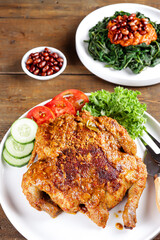 Ayam bakar Taliwang  is a traditional roast chicken from Lombok Indonesia on a wooden background, served with plecing.