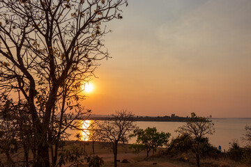 Pôr do sol entre árvores sobre o lago em Brasília, Brasil.