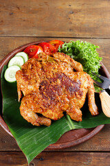 Ayam bakar Taliwang  is a traditional roast chicken from Lombok Indonesia on a wooden background.