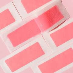 Pink wax strips for depilation on a pink background. Epilation, depilation, unwanted hair removal. Top view.