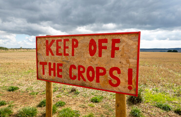 Oxfordshire, England, UK. 2021. A farmers hand painted sign in red paint saying, keep off the crops ! I a field in Cotswolds area of the UK.