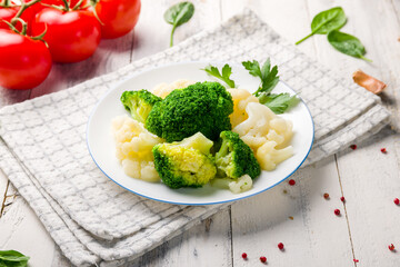 steamed broccoli with cauliflower on white plate on white wooden table