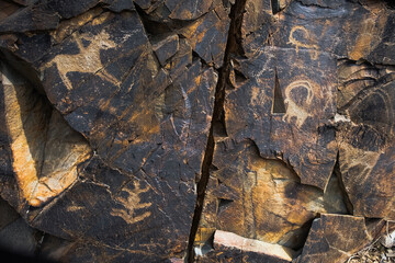 Ancient cave paintings on rocks. Bronze Age, Iron Age and Middle Age rock art. Tanbaly tas...