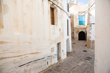 Fototapeta na wymiar The architecture of the island of Ibiza. A charming empty white street in the old town of Eivissa