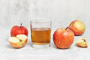 Glass with fresh apple juice with sliced apples at the concrete background. Autumn homemade juice preparation