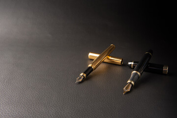 Fountain pen, beautiful details of two beautiful fountain pens placed on black leather, selective focus.