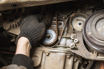 An auto mechanic checks the condition of an old timing belt during a technical inspection, close-up