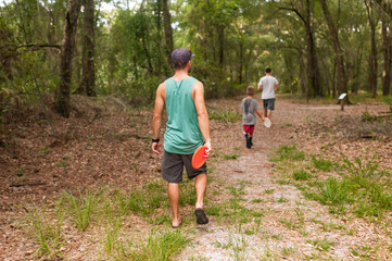 Family playing frisbee in the forest walking in wilderness nature