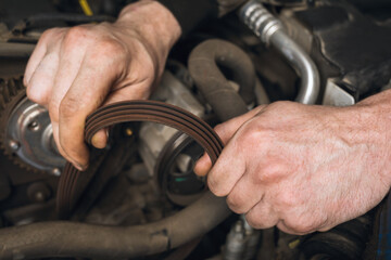 An auto mechanic checks the condition of the alternator belt during a technical inspection