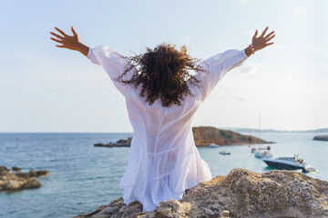 Unrecognizable curly haired woman raising her arms in happiness. Concept of freedom