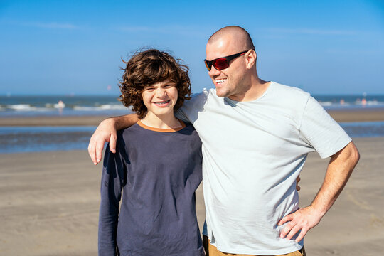 Father with a  teenager son smiling, spending time together at the seaside.  Happy boy with  dental braces.