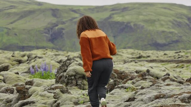 Woman Hiking Over Moss Covered Rocks In Landscape