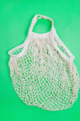 The concept of zero waste without plastic. Cotton reusable mesh shopping bag on a green background.