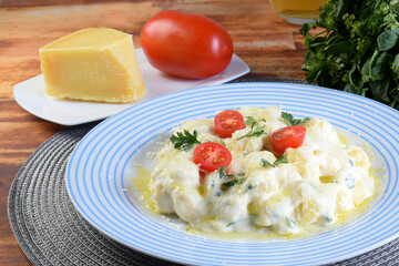 delicious gnocchi pasta in white sauce with parmesan cheese, tomato, basil, herbs, healthy food from Italian and French cuisine