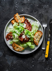 Caesar salad with bacon on a dark background, top view. Delicious brunch, appetizer, tapas