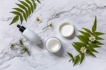 Obraz na płótnie Canvas Natural cosmetic products. Daily hygiene and female healthy skincare. Cosmetic cream and skin care serum with cammomile flofers on marble countertop. SPA natural organic beauty product.