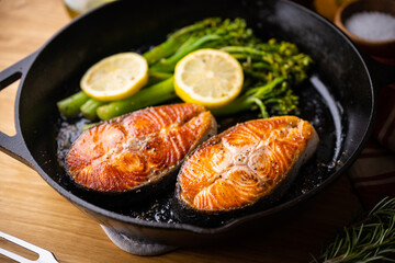 roasted salmon fillet steak with broccolini and lemon slice on iron skillet pan