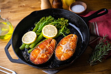roasted salmon fillet steak with broccolini and lemon slice on iron skillet pan